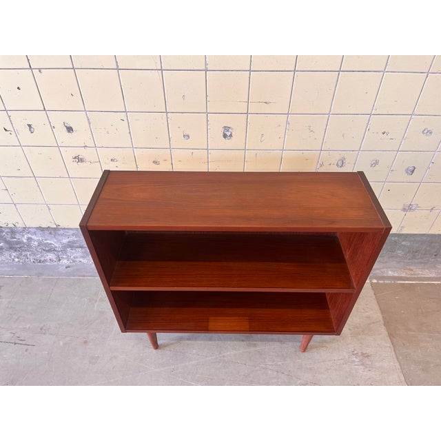 This Danish bookcase is crafted in warm teak and features a clean and functional design with balanced proportions and...
