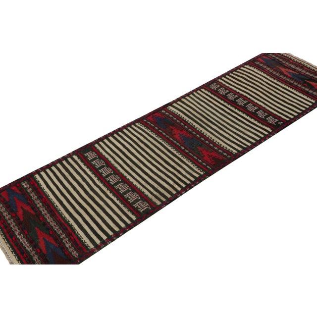 Handwoven in wool, this 2x7 vintage Afghan Baluch tribal kilim runner rug, circa 1950-1960, is an exquisite tribal piece...
