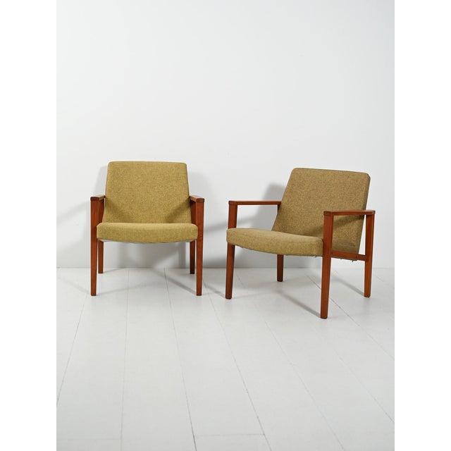 A pair of teak armchairs from the 1950s–1960s with original lime green wool upholstery; clean lines and visible joins. A...