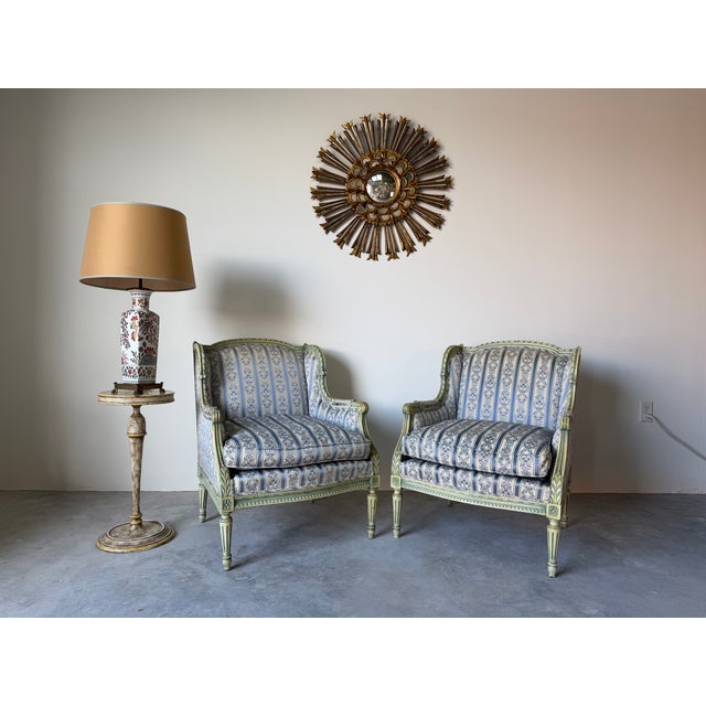 Elegant pair of 1970s French Louis XVI style armchairs featuring beautifully carved wood frames with a distressed green...