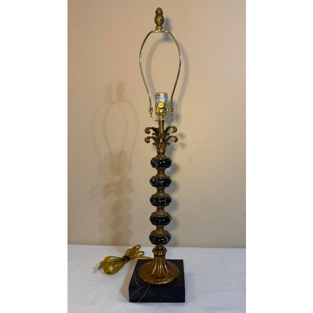 Hollywood Regency lamp alternates stacked black marble and antique gold finished metal with an acanthus leaf flourish...