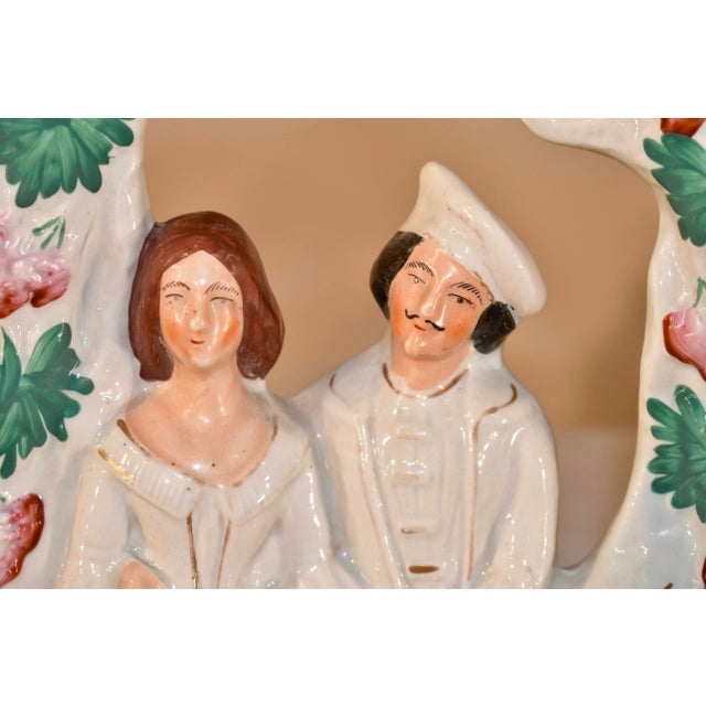 19th century Staffordshire figure group of a couple who appear to be courting sitting on a bench under an arbor with...