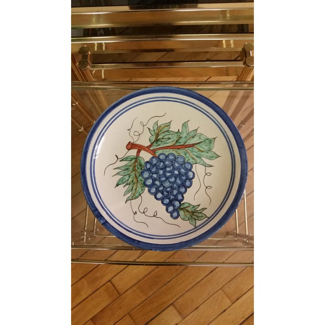 Here's a vintage Mexican redware decorative plate that features grapes. It has holes on backside for hanging on the wall....