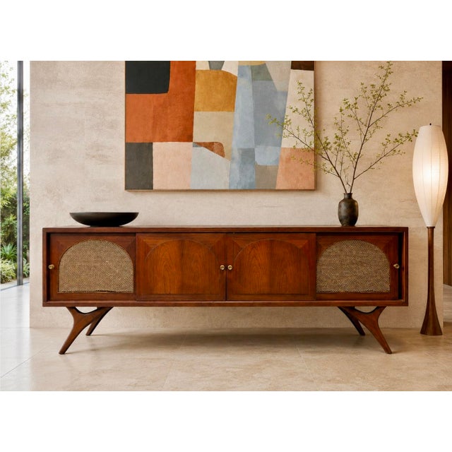 Long + Low Mid Century Modern Credenza with stunning wishbone style legs and rattan detailing, c. 1960's. Crafted in...
