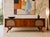 Long + Low Mid Century Modern Credenza with stunning wishbone style legs and rattan detailing, c. 1960's. Crafted in...