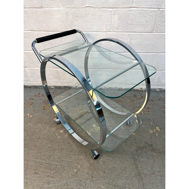 Striking Mid-Century Modern glass and chrome bar cart designed by George Mulhauser for DIA, featuring a sculptural...