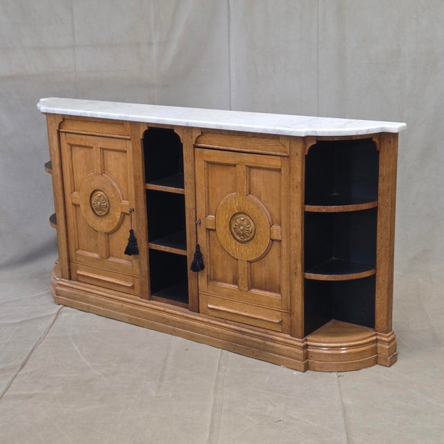 A beautiful and functional antique 1920s or 1930s oak console cabinet with a Carrera marble top. Likely made in England,...
