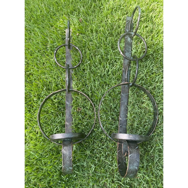 Hand-forged metal wall candle sconces with a dark patinated finish accented by subtle verdigris tones. Crafted in India,...