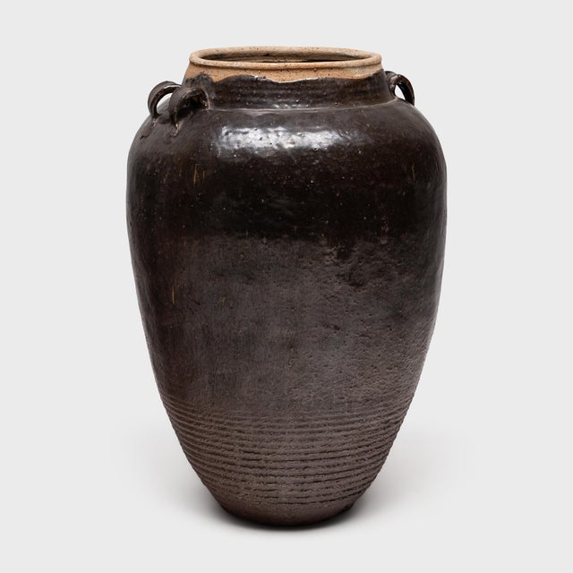 This large stoneware vessel is a Qing-dynasty (1644-1911) wine jar, originally filled with wine and spirits made from rice...