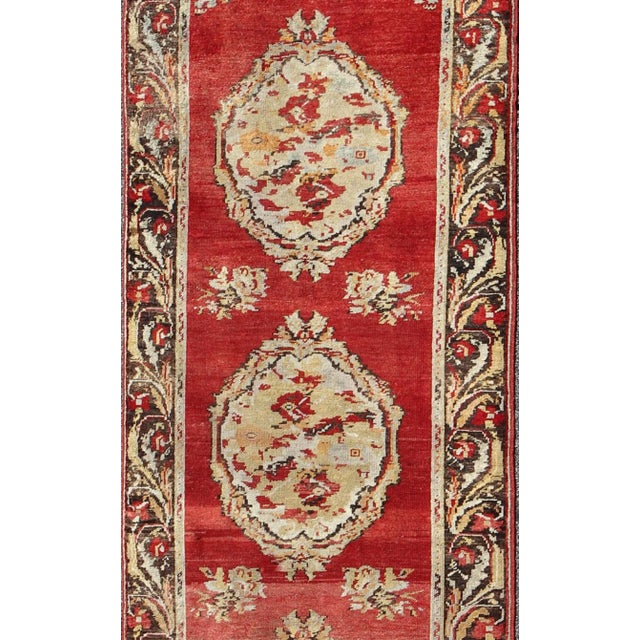 This antique Turkish Oushak runner from the early 20th century displays an elegant four-medallion center field with a...