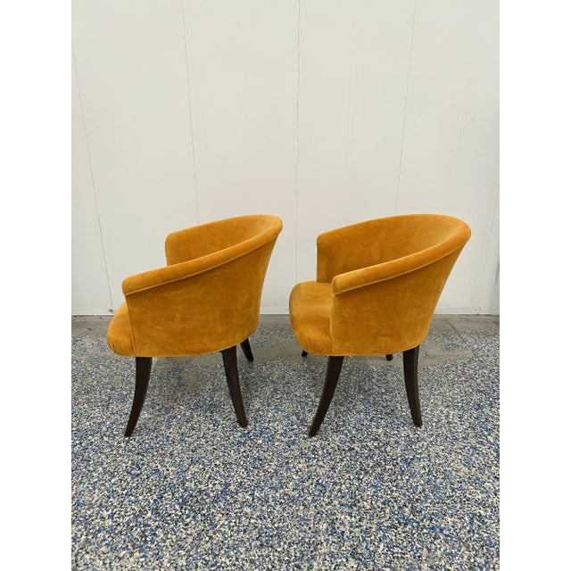 These elegant chairs feature barrel backs with rolled arms and gracefully curved legs. The bright orange velvet upholstery...