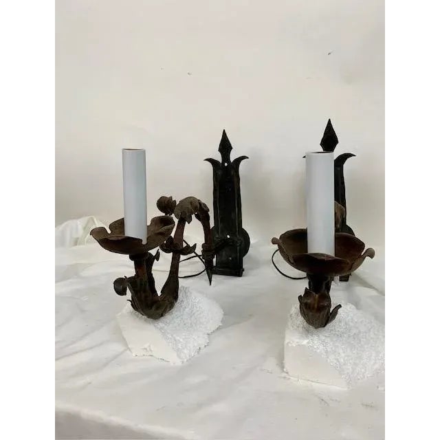 A remarkable pair of hand-forged wrought iron wall sconces from the 1930s, showcasing the beauty and craftsmanship of...