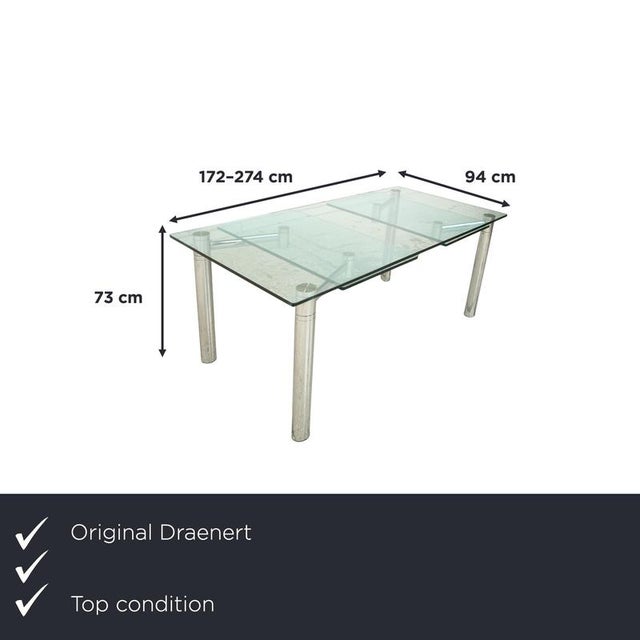 The Casanova by Draenert is a rectangular glass table with a clean, minimalist design and round metal legs and a chrome...