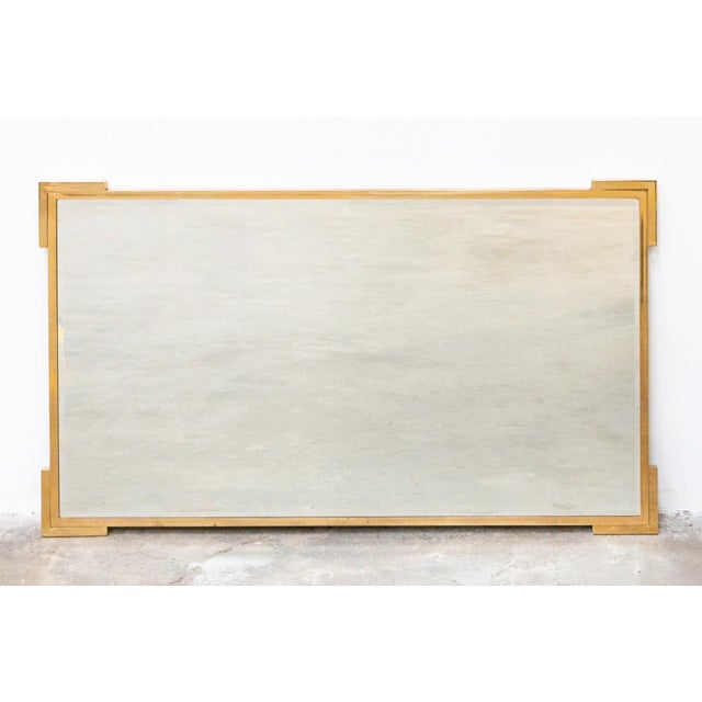 1960s/70s mirror with a gilded brass frame. The glass has beveled edges and is free of defects; the frame shows minor...