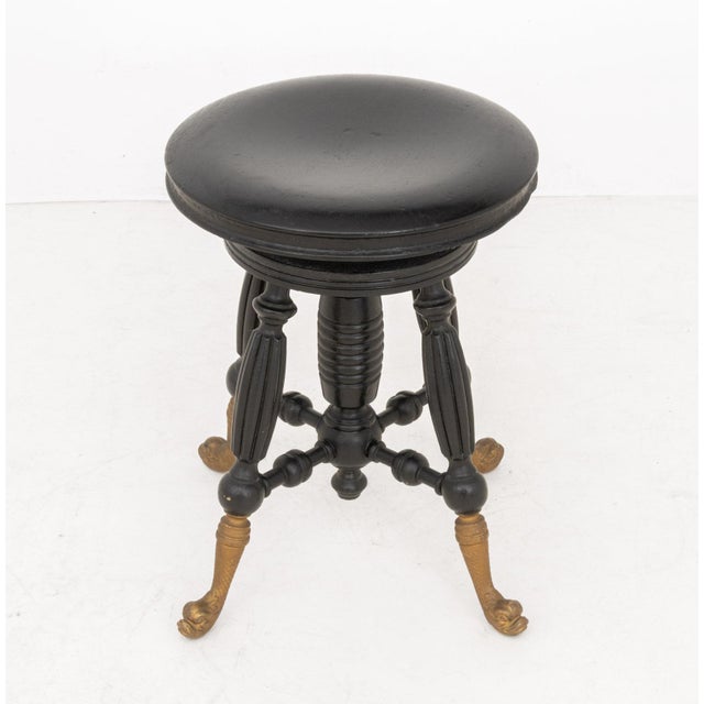 Victorian Ebonized Circular Piano Stool, circa 1900, with brass porpoise form feet. 18.5" H x 14" Diameter. Provenance:...