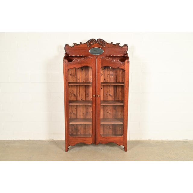 An exceptional antique Victorian bookcase cabinet In the manner of R.J. Horner & Co. USA, Circa 1880s Carved cherry wood,...