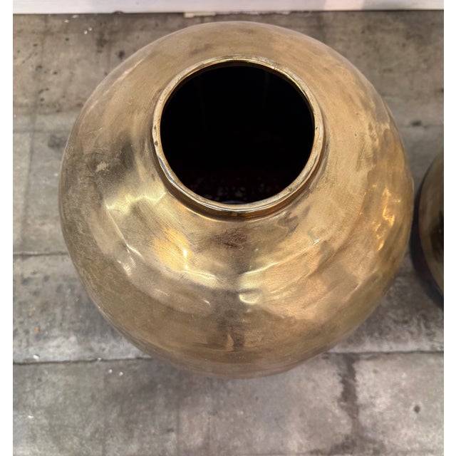 A sculptural pair of oversized Italian vases from the 1970s. The contrast between the warm, reflective brass and the matte...