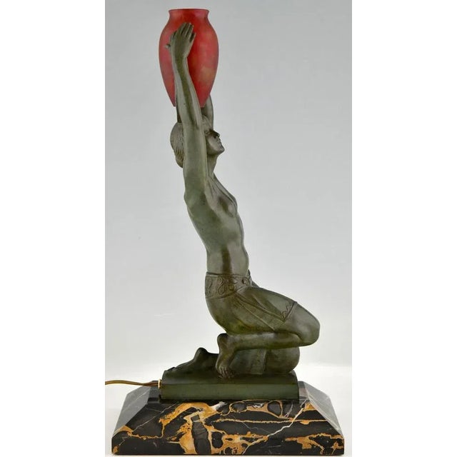 Art Deco lamp kneeling nude holding a vase by Fayral, Vers L'oasis, with Daum glass shade. Patinated Art Metal on Portor...