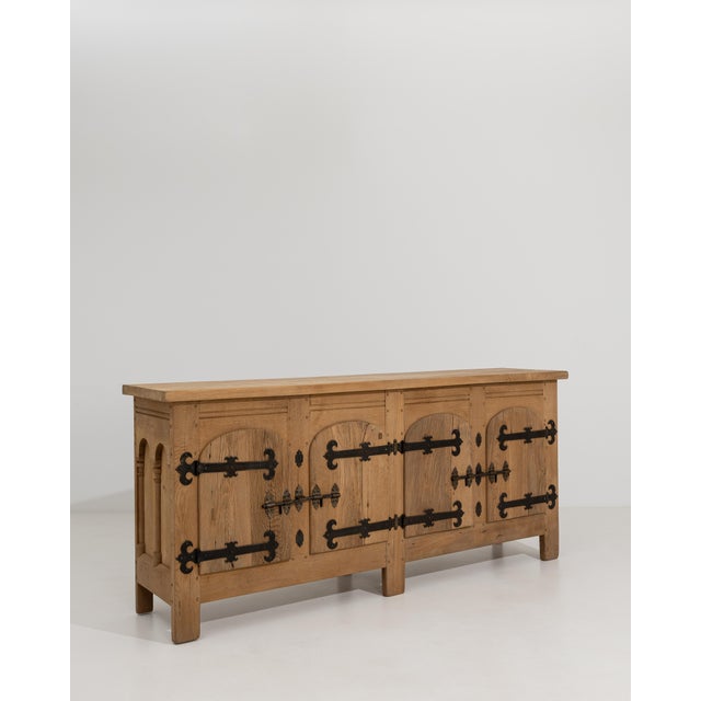 A Brutalist oak buffet featuring a solid wood structure with iron hardware accents. The piece is defined by its bold,...