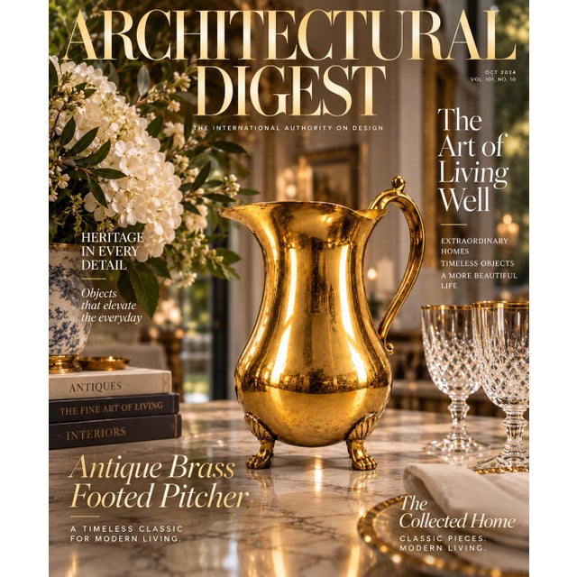 A polished brass pitcher featuring a bulbous body elevated on four ornate paw feet, paired with an elegant scrolled handle...