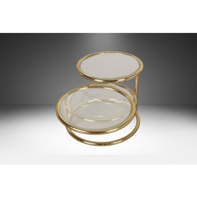 A beautiful Mid Century Modern vintage 3-tier brass and glass swivel coffee table in the style of Milo Baughman. Features...