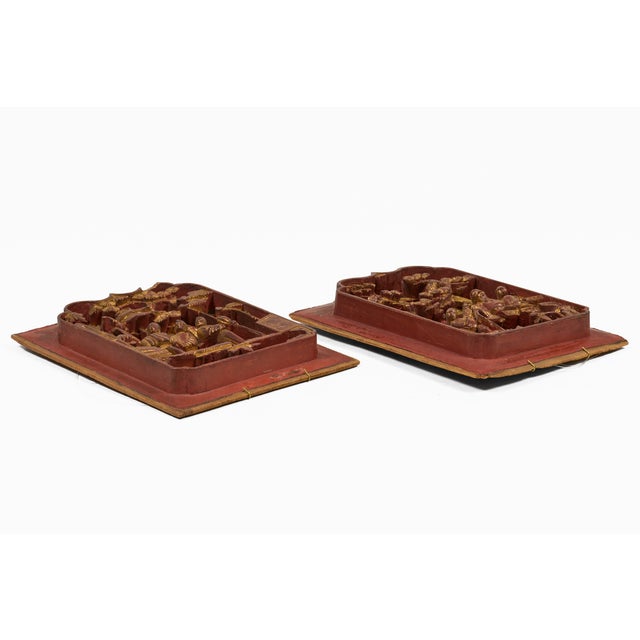 A pair of antique Chinese wood carvings decorated with gold leaf over a cinnabar red lacquered surface depicting figural...