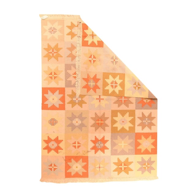 The rich chocolate field displays a five by seven array of red, straw and cream rows of five triangle-assembly stars, with...