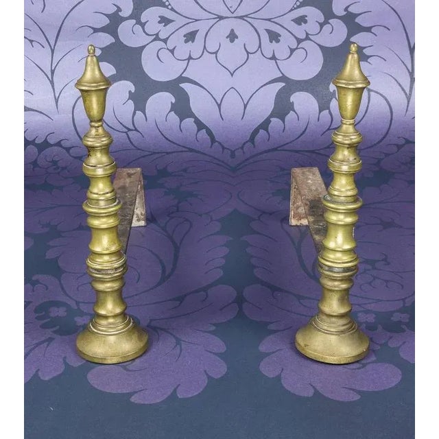 This pair of ornate French brass andirons, circa 1910, are comprised of elegantly stacked turned components. With...