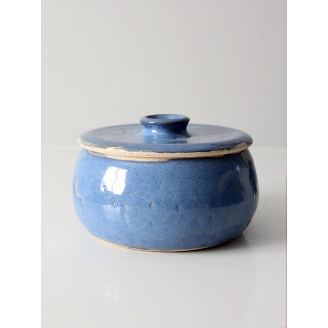 This is a vintage studio pottery covered bowl. Signed by the artist, the handmade ceramic jar features a bright sky blue...