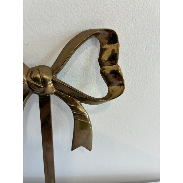 A charming vintage wall hook cast in solid brass in the shape of a bow, with looped ribbon ends and a knotted center...