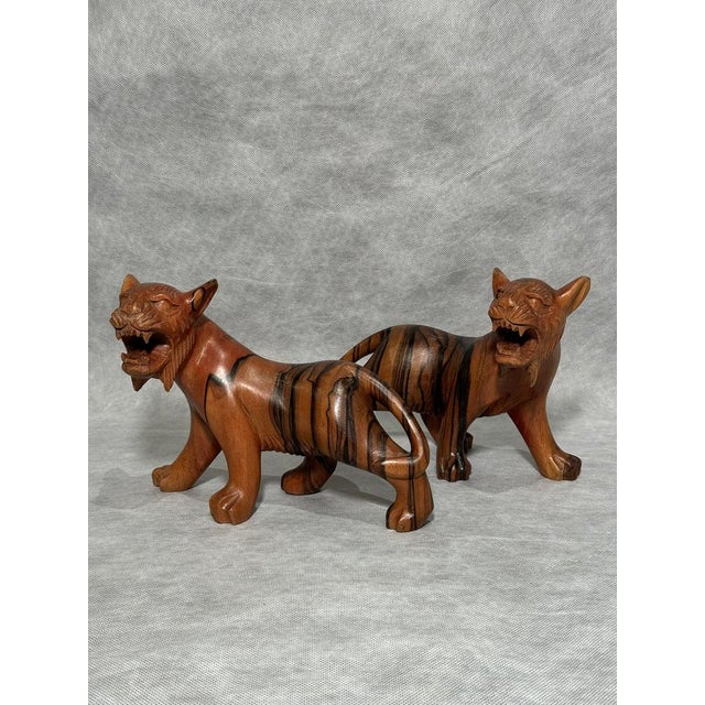 A striking pair of hand-carved wooden tiger sculptures made from richly grained exotic wood.Well preserved with light wear...