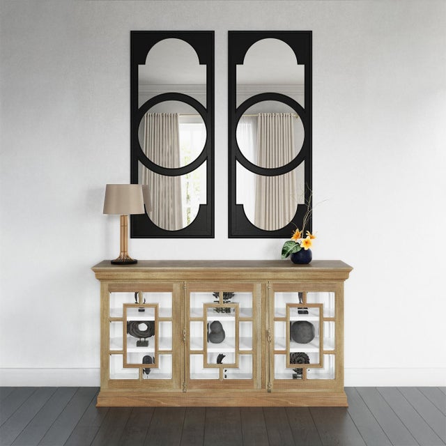 Framed in a fruitwood finish, its glass-paneled doors feature geometric fretwork in a stylized pattern evocative of...