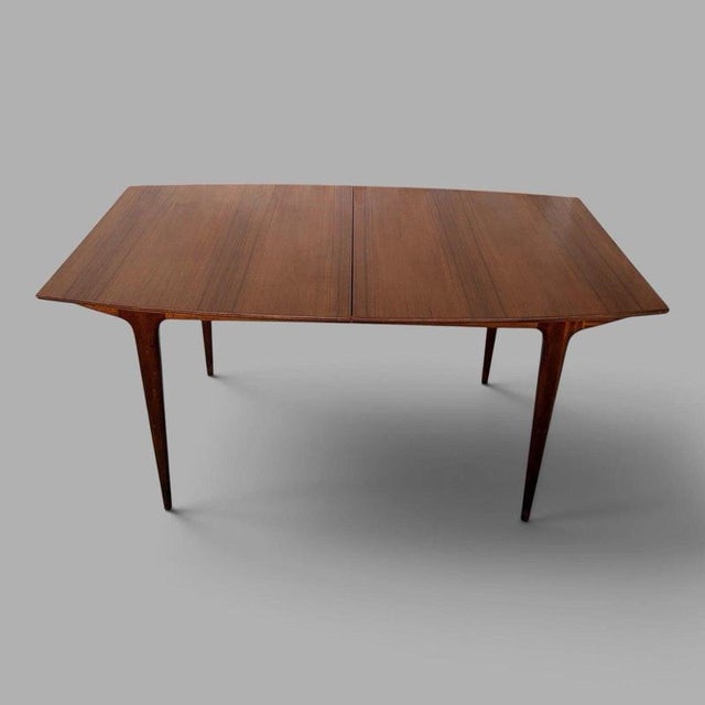 A beautifully proportioned mid-century teak extending dining table by A.H. McIntosh of Kirkcaldy, featuring an integrated...
