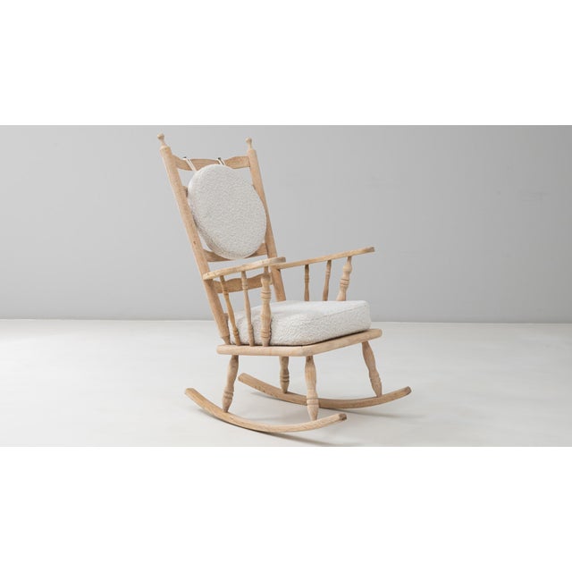 This 20th Century French spindle-back oak rocking chair offers a charming blend of rustic craftsmanship and contemporary...