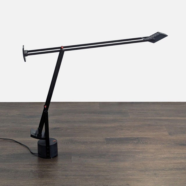 This Artemide desk lamp features a sleek black design with adjustable arms for flexible lighting. Perfect for workspaces...