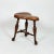A turned mahogany three-legged saddle-seat stool with a molded leather seat and nailhead trim; on turned legs, joined by...