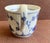 Fine white porcelain with vertical fluted texture; hand painted floral motif, a blue ring on inner rim and a high looped...