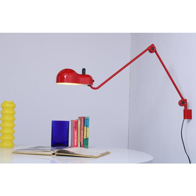 This red Topo wall light showcases true Italian signature blend of style and functionality. The articulating metal arm and...