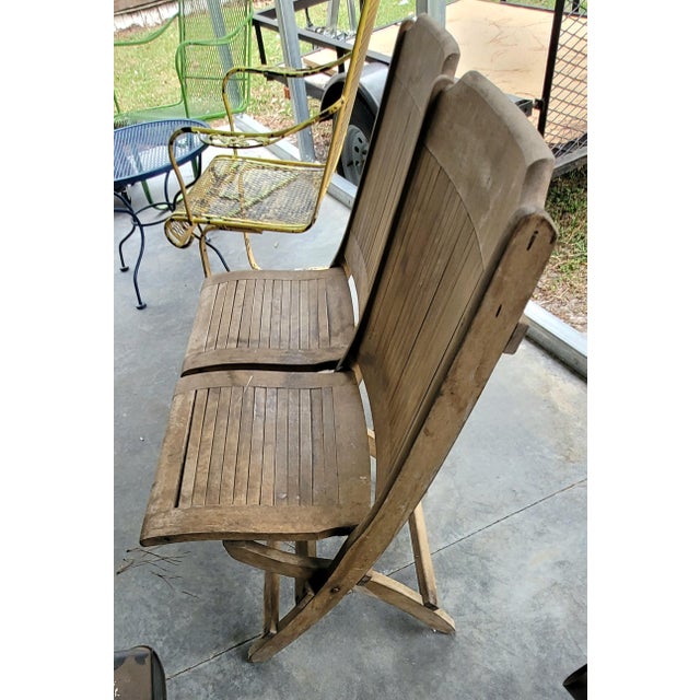 Vintage double folding theater-style bench crafted from solid wood with a slatted seat and back design. This rustic piece...