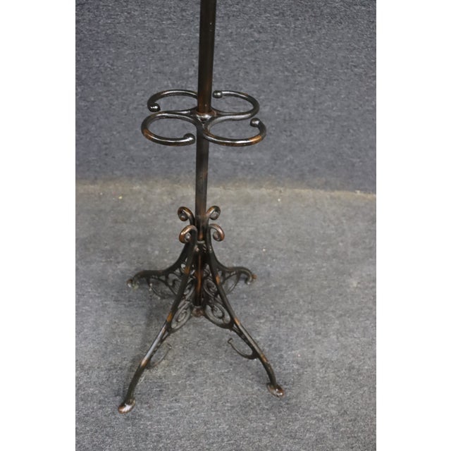 Ornate iron hall tree or coat rack featuring a decorative scrolling base, multiple coat and hat hooks, and an integrated...