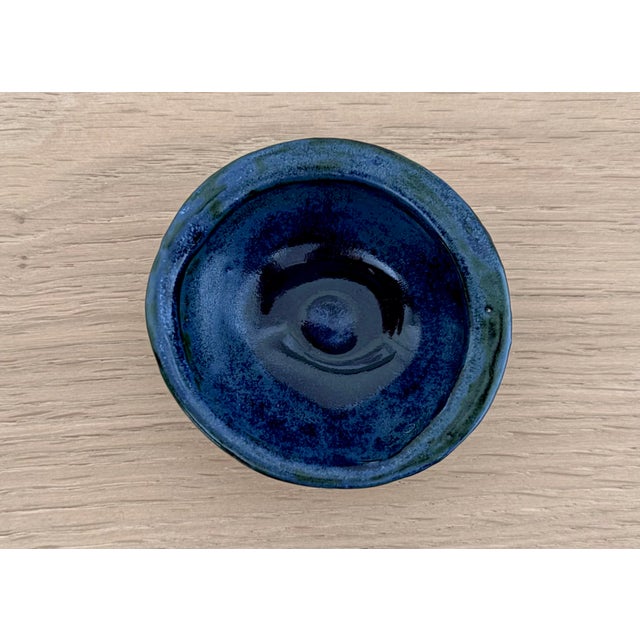 A small signed studio pottery bowl or ring dish with a richly layered cobalt blue and blue-green glaze. The hand-thrown...