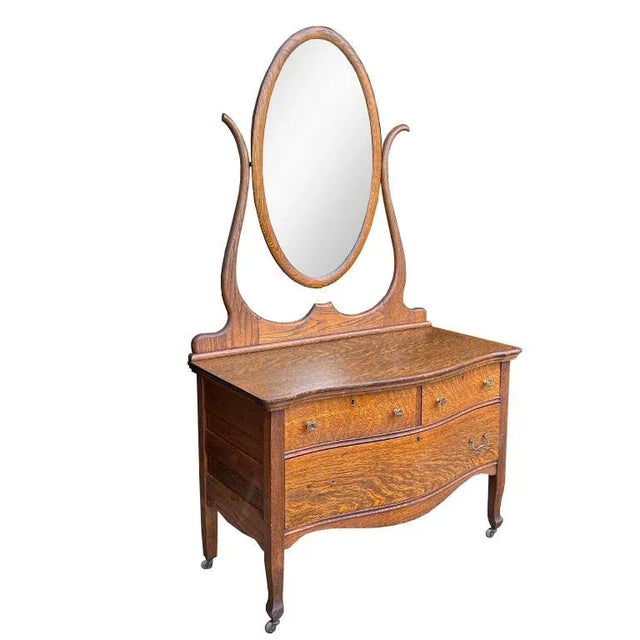 A stunning tiger oak wood dresser with an oval mirror. Sourced from an estate in Kansas, this gorgeous wood piece has...