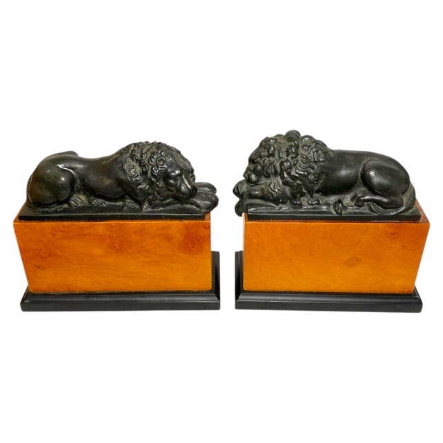 Stunning pair of bronze resting lion bookends in the style of Antonio Canova. The lions sit atop a cherry wood base. These...
