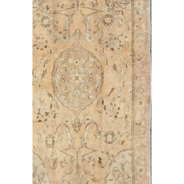 This beautiful vintage rug from mid-20th century Turkey features an intricate design. The light peach colored ground is...