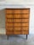 Six stacked drawers set above round tapered legs offer vertical storage. Sculpted lip handles span each drawer front for a...