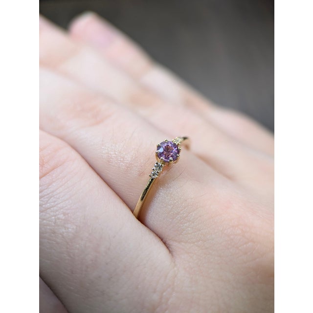 A purple sapphire sits in a rich royal purple at the centre of this solid 14K yellow gold ring, surrounded by four earth-...
