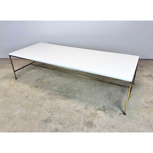 A dramatic mid century modern vitrolite glass and brass finish frame coffee table attributed to Paul McCobb circa...