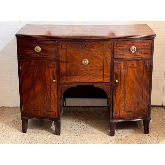 A 19th century English mahogany server with a rectangular top above a central drawer flanked by cupboard doors. The case...