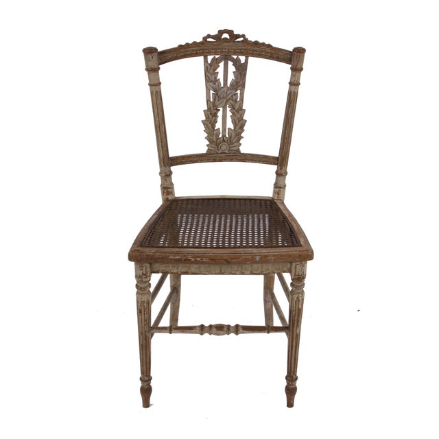 This antique pair of wood & cane chairs from late 18th Century France features turned legs and carved splat with a laurel...