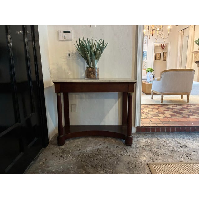 Classic French Empire style mahogany console table with a white veined marble top. Clean, architectural lines with a...